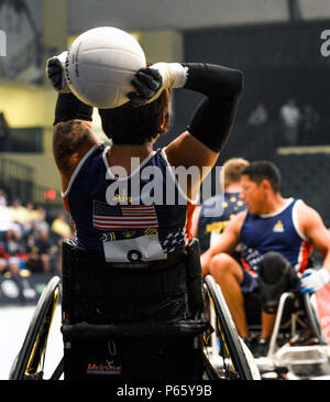 Team US und Team Australia treten bei den Invictus Games 2016 am 11. Mai in der ESPN Wide World of Sports in Orlando im Halbfinale für Rollstuhlrugby an. Ein US-Athlet wirft den Ball, um das Spiel fortzusetzen. Das Spiel demonstriert adaptive Sportfähigkeiten, Teamwork, Strategie und Mobilität für verwundete Servicemitarbeiter. Das US-Team gewann und erreichte das Finale gegen Großbritannien oder Dänemark, was die internationale Beteiligung und den Wettkampfgeist der verletzten Militärangehörigen hervorhob. Stockfoto