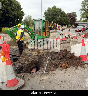 Mini Bagger neben Rohrgraben in Fahrbahn mit temporären Straßensperre. Ein 4251 Hemel Hempstead, Berkhamsted Straße Sanierung, Hertf Stockfoto