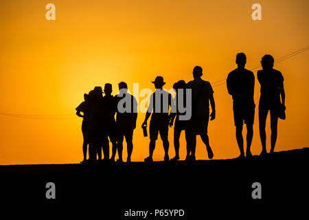 Eine Gruppe junger kolumbianischer Touristen zu Fuß auf die Steinmauern, die die koloniale Stadt, während des Sonnenuntergangs in Cartagena, Kolumbien. Stockfoto