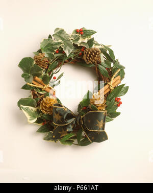 Nahaufnahme der Hand-made Christmas Wreath mit frischem Efeu und Laub mit Zimtstangen und grün + Gold Ribbon Stockfoto