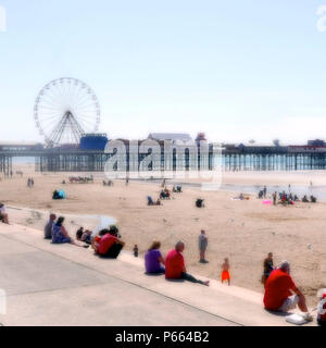 Soft Focus auf Menschen auf Blackpool Beach vor dem Pier und das Riesenrad an einem heißen Sommertag Stockfoto