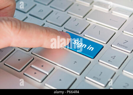 Konzeptionelle Leute Finger die ENTER-Taste auf dem Laptop Tastatur in Makro. Anmelden Inschriften auf dem Grau Silber Tastatur Taste schließen Stockfoto