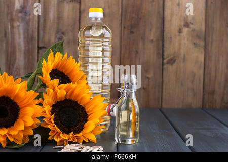 Dodsolnechnoe Öl in eine Flasche mit einem großen und einem kleinen, ein Blumenstrauß aus Sonnenblumen Blumen, auf einem winzigen Hintergrund und verstreuten Samen. Natürliches Produkt, rustikalen Stil. Platz kopieren Stockfoto