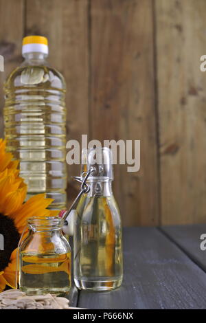 Dodsolnechnoe Öl in eine Flasche mit einem großen und einem kleinen, ein Blumenstrauß aus Sonnenblumen Blumen, auf einem winzigen Hintergrund und verstreuten Samen. Natürliches Produkt, rustikalen Stil. Platz kopieren Stockfoto