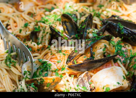 Spaghetti mit Muscheln und Tintenfisch mit Tomatensoße nur diente in der Kupfer Topf. Traditionelle Küche Süditaliens. Selektiver Fokus Stockfoto