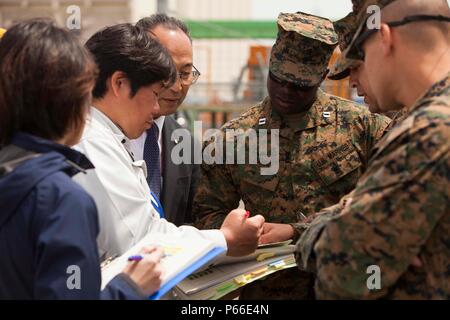 SENDAI, Japan - Kapitän Emmanuel Stimmen, der Offizier die Übung für die Artillerie Relocation Training Programm 16-1, arbeitet mit japanischen Einschiffung Fremdfirmen das Entladen der Artillerie in Sendai Port Überwachung am 9. Mai 2016. Stimmen ist mit 3.Bataillon, 12 Marine Regiment, 3rd Marine Division, III Marine Expeditionary Force in Camp Hansen, Okinawa, Japan beruht und sich von Washington, D.C. Stockfoto