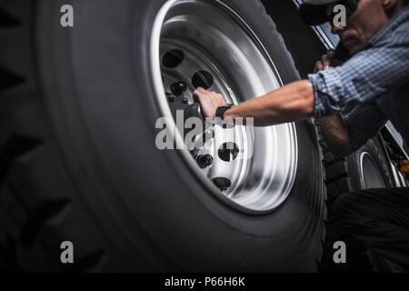 Kaukasische Treiber prüfen Halb lkw-Räder. Transport Industrie. Stockfoto