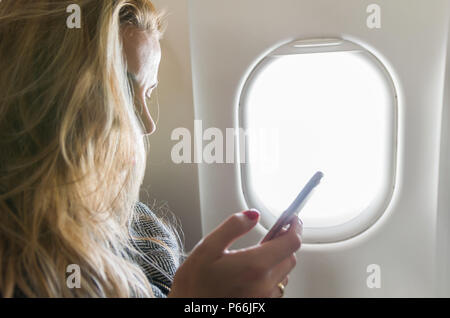 Junge blonde Frau mit Smartphone auf Flugmodus Stockfoto