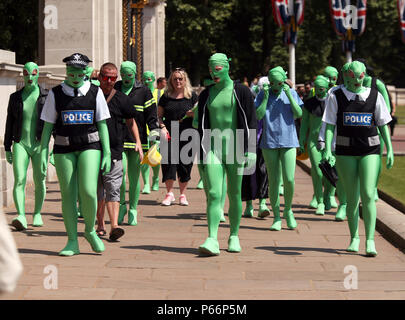 Eine Gruppe von Menschen in Grün morphsuits im Green Park, London gekleidet. Briten werden die heißesten Temperaturen des Jahres für den vierten Tag in Folge diese Woche zu genießen, mit dem Mercury vorhergesagt steigen auf 32 C (105 F). Stockfoto