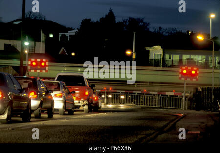 Ein Zug Geschwindigkeiten hinter dem Bahnübergang als Ampel wartet auf die Barrieren in dieser Nacht Szene in Narborough, Leicestershire zu heben. C2000 Stockfoto