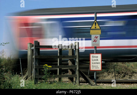 Ein Zug Geschwindigkeiten übergeben eine unbemannte farm Kreuzung als Zeichen der potentiellen Gefahr warnen. C2000 Stockfoto