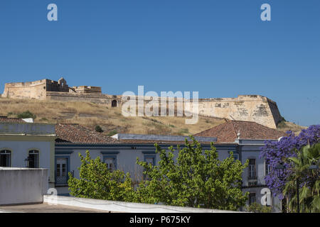 Häuser von Castro Marim und einem Ausblick auf die mittelalterliche casle auf dem Hügel mit dem gleichen Namen, durch die Schutzmauer umgeben. Strahlend blauen Himmel. Castro Marim, Stockfoto