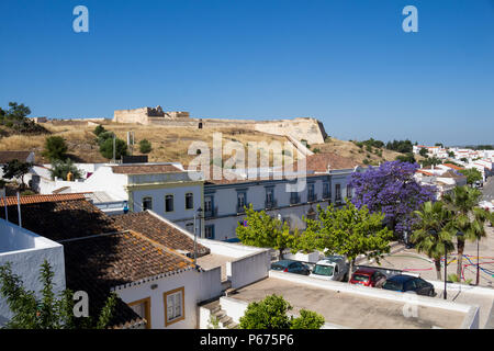 Häuser von Castro Marim und einem Ausblick auf die mittelalterliche casle auf dem Hügel mit dem gleichen Namen, durch die Schutzmauer umgeben. Strahlend blauen Himmel. Castro Marim, Stockfoto