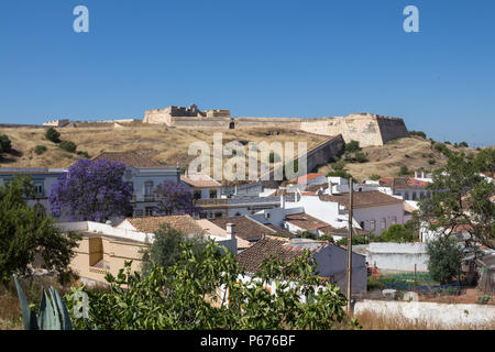 Häuser von Castro Marim und einem Ausblick auf die mittelalterliche casle auf dem Hügel mit dem gleichen Namen, durch die Schutzmauer umgeben. Strahlend blauen Himmel. Castro Marim, Stockfoto