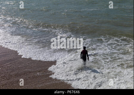 Mann in Anzug Vorbereitung im rauen Wasser zu schwimmen, Brighton, Großbritannien Stockfoto