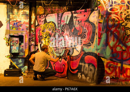 London Waterloo Leake Street Graffiti artist Sprühdose Maler Malerei grau grau silbernen Linien über alte Kunst in schwarz PVC-Handschuhe Stockfoto