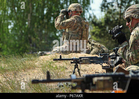 Das Spähen durch ein Fernglas, Aufklärer, Pop-up-Ziele und Einstellungen zu den Soldaten feuern M240B Maschinengewehre während B Batterie, Field Artillery Squadron, kombinierte Waffen Sortiment 2 Reiterregiment, 25. Mai, an Adazi Militärbasis, Lettland erzählen. Soldaten schossen auch M2 50 Kaliber Maschinengewehre nach Abschluss Tabelle XII schießwesen mit M777 A2 abgeschleppt Haubitzen früh in der Woche. (U.S. Armee Foto von Sgt. Paige Behringer, 10 Drücken Sie Camp Headquarters) Stockfoto