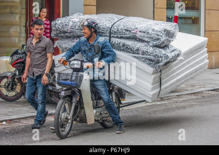 Hanoi, Vietnam - da Autos teuer sind und der Verkehr verrückt, in Vietnam Motorroller gebrauchte Ware an Stelle des Autos zu transportieren, oft überlastet sind Stockfoto