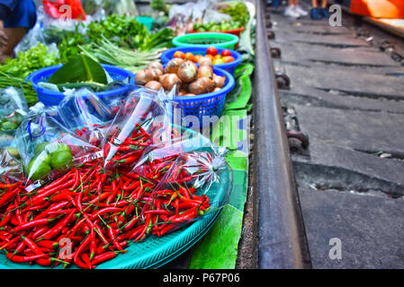 Verkauf von Speisen auf der Maeklong Railway Markt in Thailand. Stockfoto