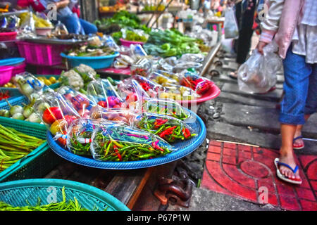 Verkauf von Speisen auf der Maeklong Railway Markt in Thailand. Stockfoto