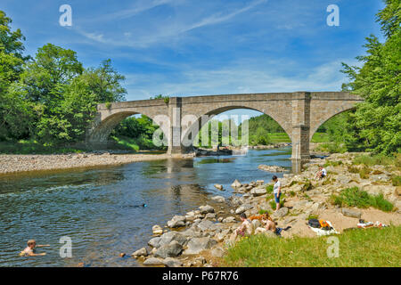 POTARCH BRÜCKE ÜBER DEN FLUSS DEE ABERDEENSHIRE EINE SEHR HEISSE SOMMER TAG MIT MENSCHEN UND HUNDEN schwimmen und PICNICING AM UFER DES FLUSSES Stockfoto
