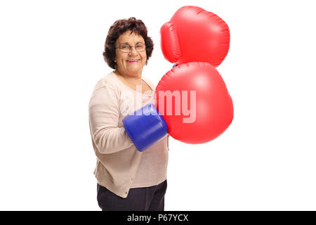 Reife Frau trägt ein Paar grosse Boxhandschuhe auf weißem Hintergrund Stockfoto