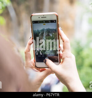 Eine Frau, die mit ihrem Handy ein Foto von einem Wasserfall während ihrer Wanderung in den Nationalpark Plitvice, Kroatien. Stockfoto