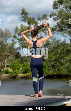 Sportlerin ihr Haar binden, bevor Sie draussen trainieren Stockfoto