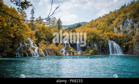 Wasserfälle in einen See von einem üppigen Wald Landschaft am Nationalpark Plitvice, Kroatien umgeben fließt. Stockfoto