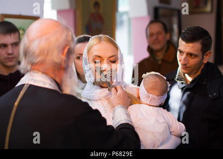 Belarus, Gomel, am 25. März. 2018. Die Prudhkovsky Kirche. Die Taufe eines Kindes. Während die Taufe eines Kindes, Eine Frau küsst ein Kreuz Stockfoto