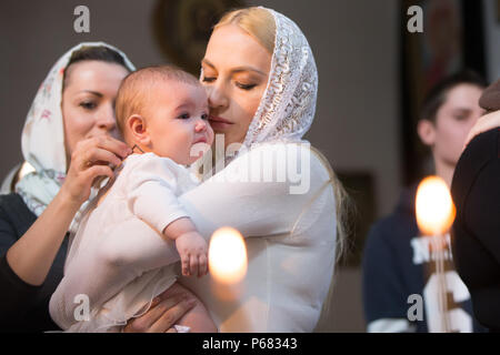 Belarus, Gomel, am 25. März. 2018. Die Prudhkovsky Kirche. Kind in die Arme der Mutter. Taufe des Babys. Akzeptieren Sie den Glauben. In der Kirche des Neugeborenen. Stockfoto