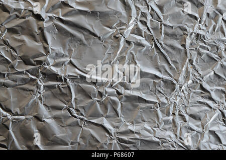 Dünne zerknittertes Blatt zerdrückt Zinn Aluminium silber Folie Hintergrund mit glänzenden zerknitterten Oberfläche für Textur. Stockfoto