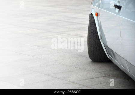 Diagonale Ansicht einer weiß-glänzend Auto, die auf einem Quadrat von grauen Fliesen steht. Stockfoto