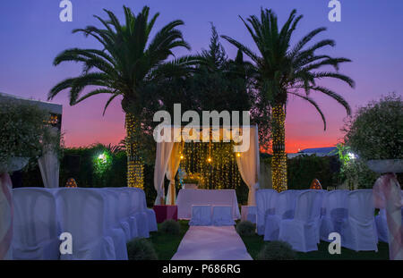 Weißer Teppich und Stühle für eine Hochzeit im Freien. Twilight Hintergrund Stockfoto
