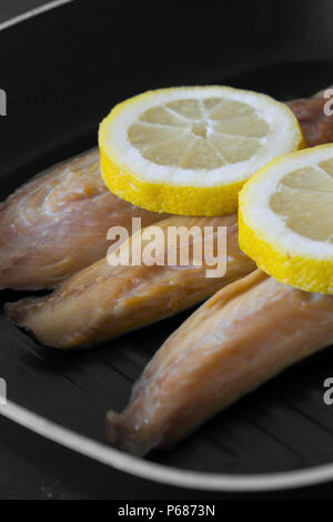 Geräucherte Makrele Fischfilets mit Zitrone in einer Bratpfanne Pfanne zum Kochen mit schwarzem Holz Hintergrund vorbereitet Stockfoto