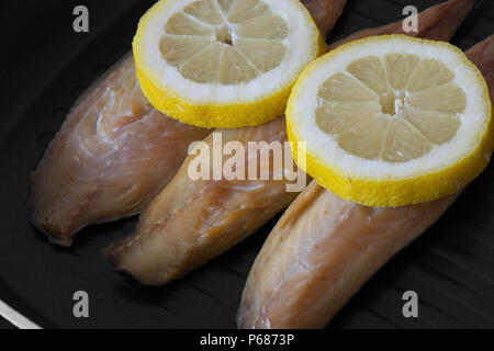 Geräucherte Makrele Fischfilets mit Zitrone in einer Bratpfanne Pfanne zum Kochen mit schwarzem Holz Hintergrund vorbereitet Stockfoto