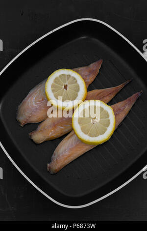 Geräucherte Makrele Fischfilets mit Zitrone in einer Bratpfanne Pfanne zum Kochen mit schwarzem Holz Hintergrund vorbereitet Stockfoto