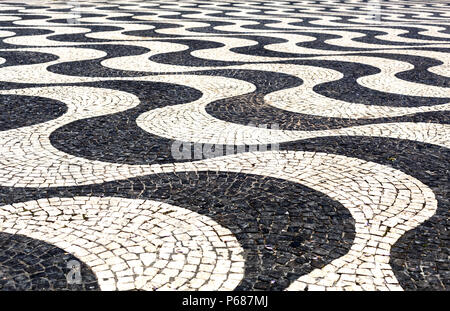 Traditionelle portugiesische Bürgersteig, mit schwarzen und weißen Steinen aus Basalt und Kalkstein, in der Fußgängerzone von Portugal entwickelt. Stockfoto