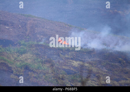 Saddleworth Moor, Manchester, UK - 28. Juni 2018. Die saddleworth Moor wildfire weiterhin am Donnerstag Nachmittag mit der Feuerwehr mit einem Hubschrauber Schaufel zu brennen, um zu versuchen, die Flammen zu löschen und das Feuer unter Kontrolle zu bekommen. Credit: Andrew Gardner/Alamy leben Nachrichten Stockfoto