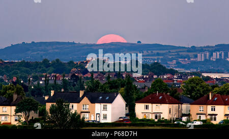 Glasgow, Schottland, Großbritannien, 28. Juni. UK Wetter: Sonnig sizzling Wetter verursacht einen klaren Himmel wie eine Erdbeere Vollmond über der Stadt erscheint über Cathkin Braes und Dechmont Hill auch als heiß oder mead Mond oder rose Moon. Credit: Gerard Fähre / alamy Leben Nachrichten Stockfoto