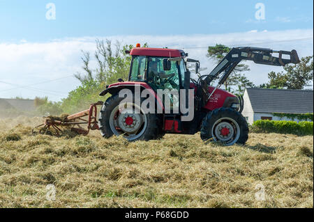 Schull, West Cork, Irland. Juni 2018. Ein Bauer arbeitet auf seinem Feld an Silage, um das trockene Wetter so lange wie möglich zu nutzen. Die Temperaturen werden für den Rest des Wochenendes in der Mitte der 20 Grad Celsius bleiben, aber ab Montag wird Regen vorhergesagt. Quelle: AG News/Alamy Live News. Stockfoto