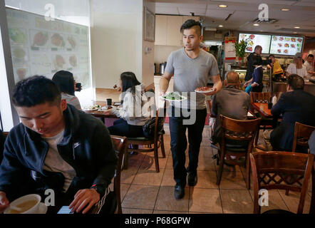 Vancouver, Kanada. 28 Juni, 2018. Anson Leung dient Kunden am HK BBQ Master Restaurant in der Vancouver Vorort von Richmond, Kanada, 28. Juni 2018. Um mit der Funktion: Junge Grill master trägt auf chinesischen Familie business in Vancouver Credit: Liang Sen/Xinhua/Alamy leben Nachrichten Stockfoto