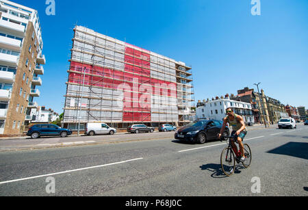 Hove Brighton, UK. 29 Juni, 2018. Ein riesiger England St Georges Cross Flag wurde umgesetzt, indem Gerüstbauer auf einem Wohnblock in St Catherines Terrasse entlang der Strandpromenade Hoves entfernt in der Nähe von Brighton. Die 120 ft 60 ft-Flag hat durch die Jahreszeiten Gerüst zur Unterstützung von England bei der WM 2018 in Russland mit der nächsten Runde Spiel gegen Kolumbien Anfang nächster Woche: Simon Dack/Alamy Leben Nachrichten gehalten werden gesetzt worden Stockfoto