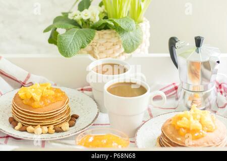 Perfektes Frühstück für 2. Fach mit Pfannkuchen mit Orange Marmelade und Muttern auf alten Platten und 2 weiße Kaffeetassen Stockfoto