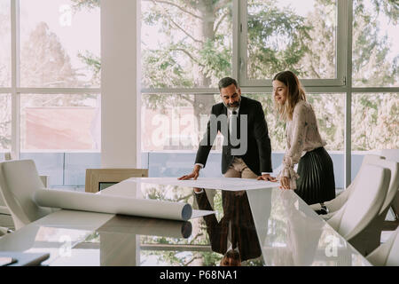 Junge Frau und ein älterer Geschäftsmann über Neues Projekt in modernen Büro besprechen Stockfoto