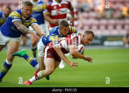 Wigan Warriors Josh Holz geht Vergangenheit Leeds Rhinos Jack Walker eine Versuchen ein Tor während der Betfred Super League match bei der DW Stadium, Wigan. Stockfoto