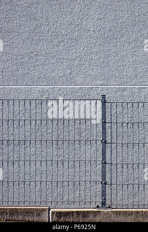 Die Details eines homogenen Lattenzaun vor einem hellen Fassade verputzt. Stockfoto