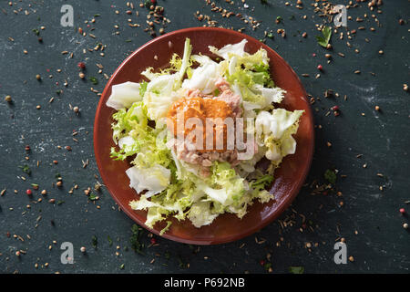 Escarola amb romesco, salatköpfe Endiviensalat mit romesco Sauce, eine typische Salat aus Katalonien, Spanien, auf braunem Steingut Teller, platziert auf einem rustikalen dunklen Stockfoto