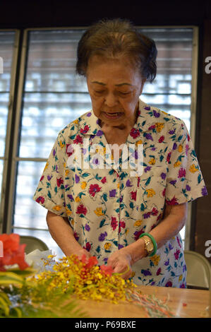 Ein freiwilliger aus dem wahiawa Rainbow Seniors bindet einen Blumenstrauß an der Wahiawa District Park, Colorado, am 27. Mai 2016. Die Blumensträuße werden auf die grabsteine an der Schofield Barracks Post Friedhof durch eine lokale Pfadfinder-truppe am Memorial Day platziert werden. (U.S. Armee Foto: Staff Sgt. Armando R Limon, 3. Brigade Combat Team, 25 Infanterie Division). Stockfoto