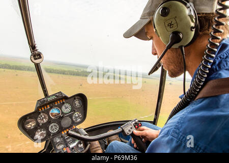 Jock am Steuerstick seines Robinson R44 Raven Hubschraubers im Northern Territory, Australien Stockfoto